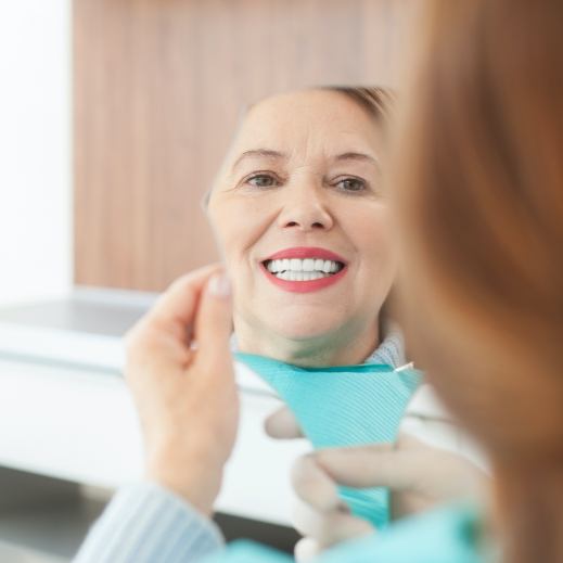 Woman looking in mirror after smile makeover