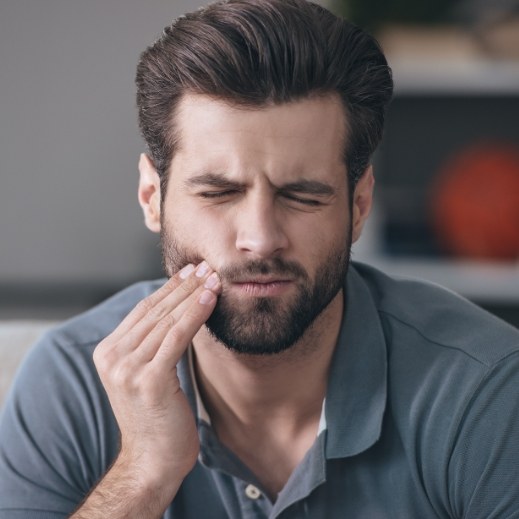 Man in need of emergency dentistry holding his cheek