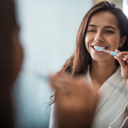 Woman brushing teeth to prevent dental emergencies