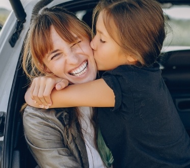Child giving mother a kiss on the cheek after children's dentistry visit