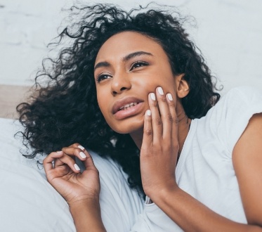 Woman in need of emergency dentistry holding cheek in pain
