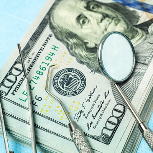 stack of money with dental tools